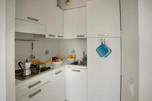 uma cozinha branca com armários brancos e um lavatório em Terrace Sur Menton - Happy Rentals em Menton