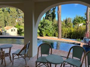 a patio with four chairs and a swimming pool at Maison d'Orange - La Pinede in Saint-Tropez