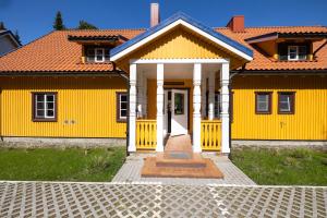 a yellow house with an orange roof at Studio@NidosBanga, By Cohost in Nida
