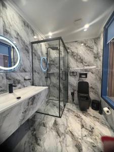 a bathroom with a glass shower and a sink at Sapar Standart Улучшенный полулюкс in Shymkent