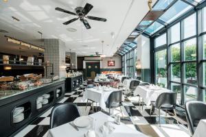 um restaurante com mesas e cadeiras brancas e janelas em Mercure Hotel Frankfurt Airport Langen em Langen