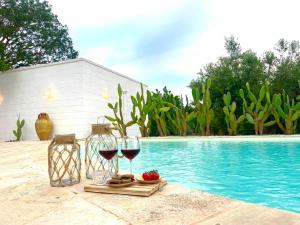 - deux verres de vin assis à côté de la piscine dans l'établissement Trulli Lamascrasciola, à Monopoli