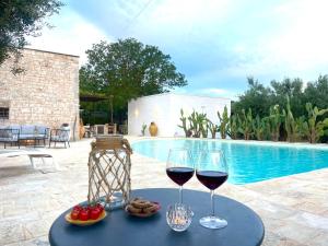 dos copas de vino en una mesa junto a una piscina en Trulli Lamascrasciola, en Monopoli