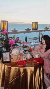 頭頓的住宿－Premier Pearl Hotel Vung Tau，两个女人坐在桌子上,边喝茶边花边