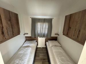two beds in a small room with a window at De Roos chalet 174 in Sint Annaland