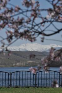 a view of a snow covered mountain range with a body of water at やすらぎの宿 菜の香 in Biei