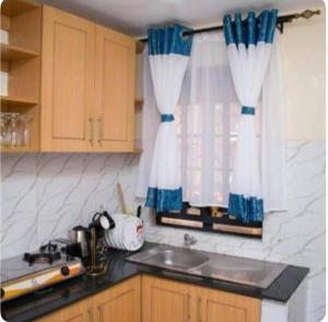 een keuken met een wastafel en een raam met gordijnen bij Kisumu 2bedroom in Kisumu