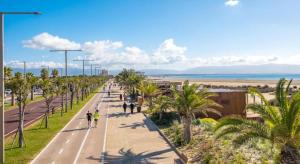 a group of people walking down a street with palm trees at Viniola Apartment in Quartu SantʼElena
