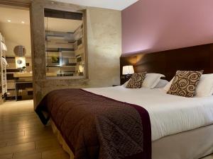 a bedroom with a large bed and a bathroom at The Originals Boutique, Hôtel de la Paix, Beaune (Qualys-Hotel) in Beaune