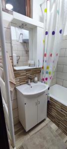 ein Badezimmer mit einem Waschbecken, einem Spiegel und einer Badewanne in der Unterkunft Etno smeštaj Stojadinović in Svrljig