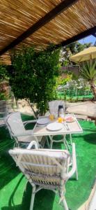 une table et des chaises blanches sous un parasol en bois dans l'établissement Mykonian Iros Suites & Villas, à Kalo Livadi