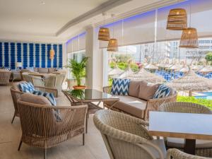 a lobby with rattan furniture and a large window at Grupotel Maritimo in Port d'Alcudia