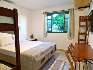 Schlafzimmer mit einem Bett, einem Schreibtisch und einem Fenster in der Unterkunft Pousada Makani Kai in Florianópolis