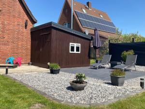 a patio with chairs and a building with solar panels at Haus HERNA by fewo-plan WING120 Nähe Nordsee, Kreidesee Hemmoor und Naturpark Wingst in Oberndorf