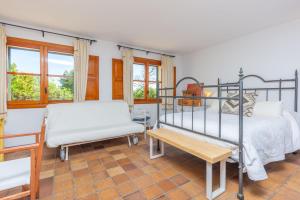 a bedroom with two beds and a bench and windows at Casa S'Olivaret -Selva- in El Port de la Selva