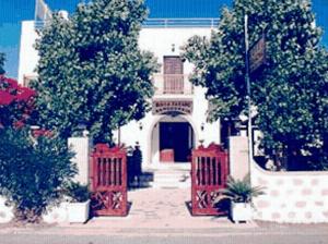 a white building with red gates and trees in front at Villa Zacharo in Skala