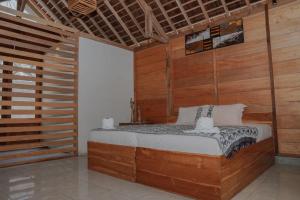 a bedroom with a bed in a room with wooden walls at Anugerah Surf & Dive in Nembrala