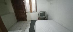 um pequeno quarto com uma cama e uma televisão em SPOT ON 93964 Guest House Pak Gatot 3 em Bandung