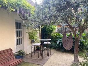 um pátio com uma mesa e cadeiras debaixo de uma árvore em Les Lauriers Duplex centre ville avec jardin em Nyons