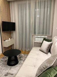 uma sala de estar com um sofá branco e uma mesa em Apartment Mari Mari em Kraljevo
