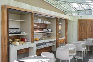 a dining room with white chairs and a bakery at Hotel Ilaria in Lucca