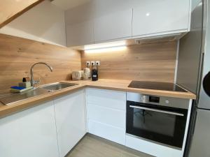 a kitchen with white cabinets and a sink and a stove at Le Duplex - Massy Centre in Massy