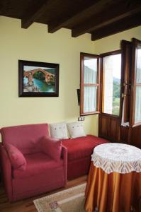 Balcón Picos de Europa في Narciandi: غرفة معيشة مع أريكة حمراء وطاولة