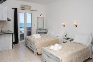 a bedroom with two beds and a kitchen with a balcony at ARTEMIS beach studios in Kalamaki