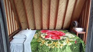 a bed in a room with a table and flowers on it at Puri Pilihani Hostel in Munduk