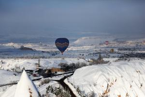 um balão de ar quente a voar sobre um campo coberto de neve em Millstone Cave Suites Hotel em Üçhisar
