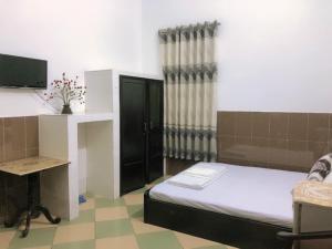 a room with a bed and a desk and a television at Kiến An Hotel Cần Thơ in Can Tho