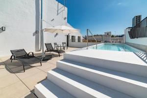 una piscina en la parte superior de un edificio con sillas y sombrilla en Slow Suites Salvador, en Sevilla