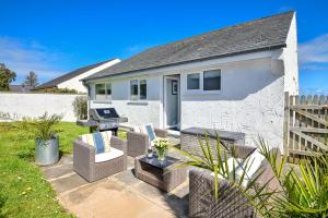 a patio with chairs and a grill in front of a house at Gwendy in Abersoch