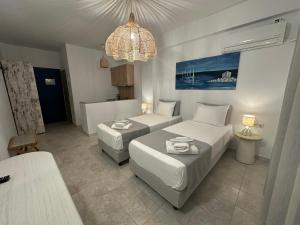 a hotel room with two beds and a chandelier at Dedes Apartments in Skala