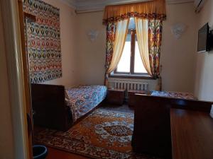 salon z łóżkiem i oknem w obiekcie Guest House Ikathouse w mieście Margilan