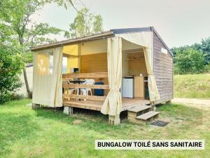 einem kleinen Schuppen mit Vorhängen und einem Kühlschrank im Hof in der Unterkunft Ludocamping in Lussas