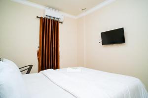 a room with two beds and a flat screen tv at Mess Rejeki Redpartner in Sampit