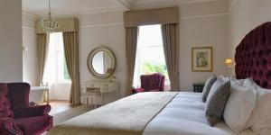 a bedroom with a large white bed and two chairs at Wellwood Manor in Pitlochry