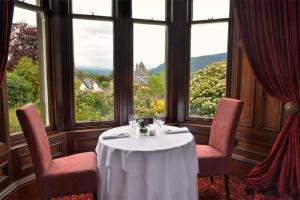 a table and chairs in a room with windows at Wellwood Manor in Pitlochry