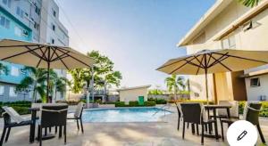 a patio with tables and chairs and umbrellas next to a pool at Standard Room at 8 Spatial by Forever-mc Condotel 8335 in Davao City