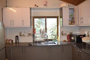 una cucina con armadi bianchi, lavandino e finestra di Royal House a Nathia Gali