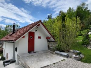 ein kleines weißes Gebäude mit einer roten Tür in der Unterkunft Babičina hišica in Mišji Dol