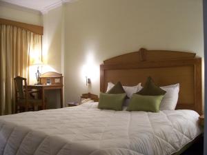 a bedroom with a large white bed with green pillows at Taj Tristar in Hyderabad