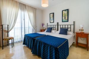 a bedroom with a bed with blue sheets and a window at Apartamentos Albir Confort - Avenida 1 dorm in Albir