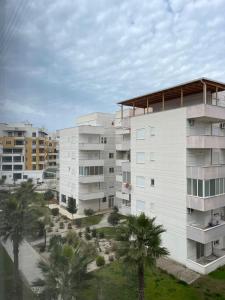 an apartment building with palm trees in front of it at Shehapi apartment in Kavajë