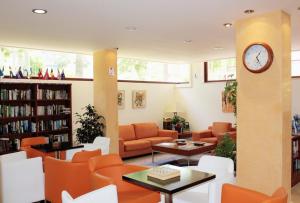 a library with orange chairs and a clock on a column at Apartamentos Albir Confort - Avenida 1 dorm in Albir
