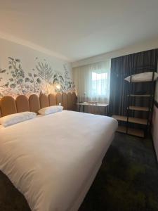 a bedroom with a large white bed and a staircase at Hôtel ibis Styles Pontivy centre Bretagne in Pontivy