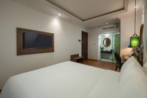 um quarto com uma grande cama branca e uma televisão em Eliana Premio Hotel Hanoi em Hanói