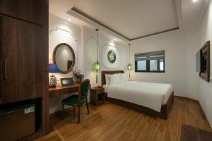 a bedroom with a bed and a desk with a mirror at Eliana Premio Hotel Hanoi in Hanoi