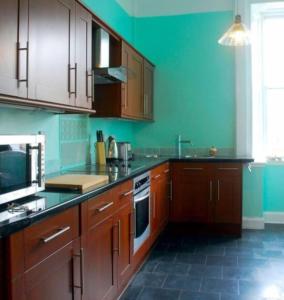 una cocina con armarios de madera y una pared verde en 6 Killean Place, en Campbeltown